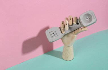 Ahşap el, mavi pembe pastel arka planda telefon tüpü tutuyor. Moda gölgesi. Sanat kavramı. Minimalizm. Yaratıcı yerleşim