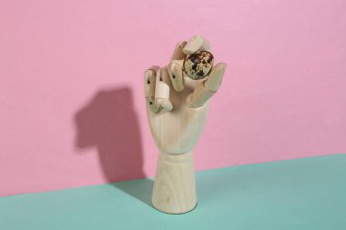 Mavi pastel arka planda bıldırcın yumurtası tutan tahta el. Moda gölgesi. Sanat kavramı. Minimalizm. Yaratıcı yerleşim
