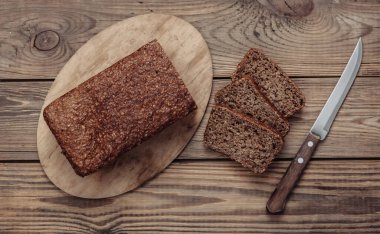 Tahta arka planda bıçaklı tam tahıllı çavdar ekmeği.