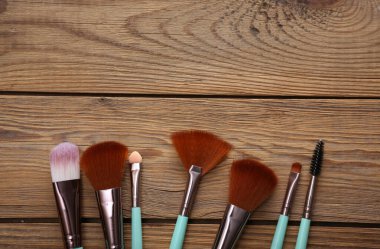 Ahşap arka planda makyaj fırçaları.