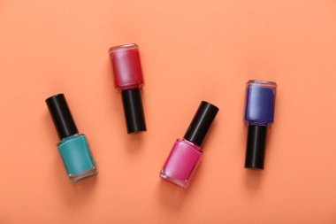 Turuncu arka planda renkli oje şişeleri. Üst görünüm