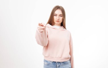 Beyaz arka planda sana işaret parmağı gösteren genç ve ciddi bir kadın.