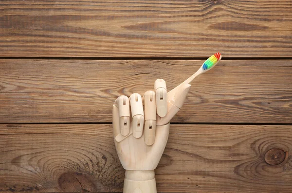 Wooden hand holds eco toothbrush on wooden background