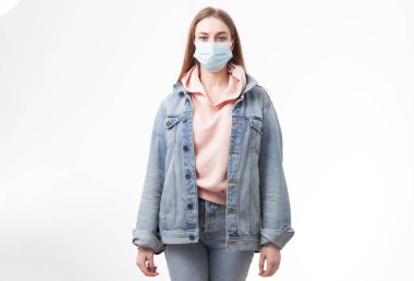 Tıbbi maskeli genç bir kadın beyaz arka planda izole edilmiş.