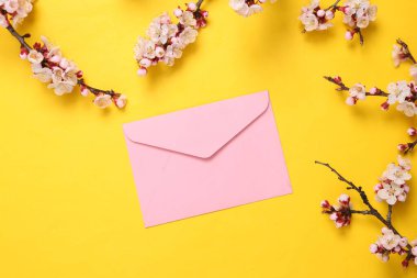 Zarf ve sarı arka planda güzel çiçek dalları. Düz yatış, üst görünüm.