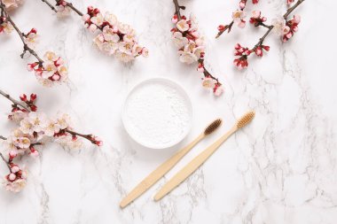 Eko bambu diş fırçaları, diş fırçası ve mermer arka planda güzel çiçek açan dallar. İlkbahar, eko konsepti. Düz yatış, üst görünüm.