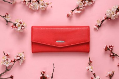 Kırmızı çanta ve pembe arka planda güzel çiçekli dallar. İlkbahar, güzellik konsepti. Düz yatış, üst görünüm.