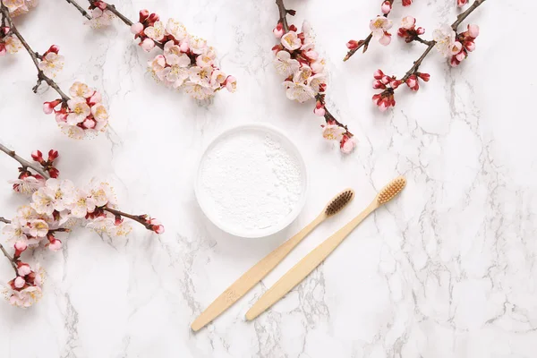 Eko bambu diş fırçaları, diş fırçası ve mermer arka planda güzel çiçek açan dallar. İlkbahar, eko konsepti. Düz yatış, üst görünüm.