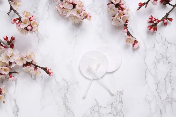 Hijyenik pamuk pedler ve kulak çubukları çiçek açan dallarla mermer bir arka planda. Hijyen kavramı