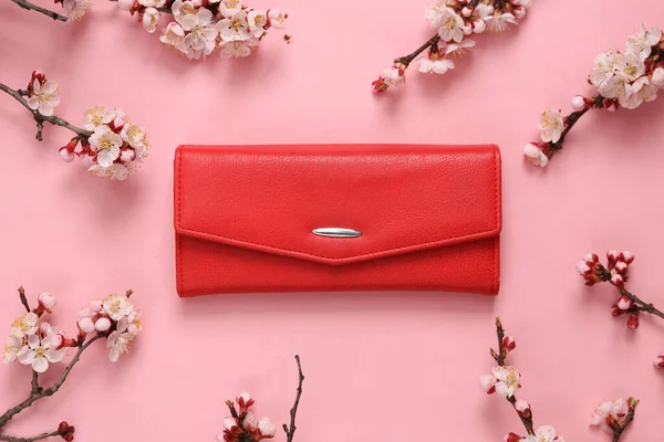 Kırmızı çanta ve pembe arka planda güzel çiçekli dallar. İlkbahar, güzellik konsepti. Düz yatış, üst görünüm.