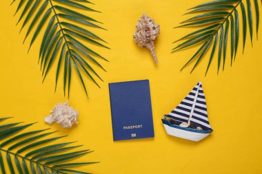 Deniz kabukları, yelkenli, pasaport, sarı arka planda palmiye yeşili yapraklar. Seyahat konsepti. Tropikal kompozisyon. Üst Manzara. Düz yatıyordu