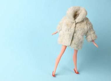 Mavi arka planda, kürk ceketli bebek mankeni. Minimalizm moda çekimi. Sanat kavramı