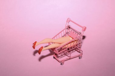 Alışveriş arabasında bebek bacaklı minimalist bir düzen. Sanat kavramı