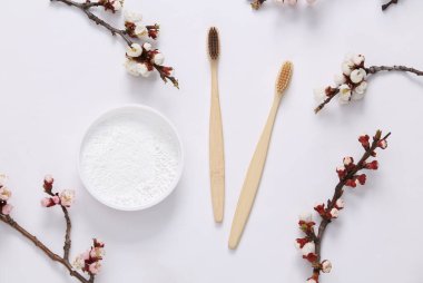 Eko bambu diş fırçaları, diş fırçası ve beyaz arka planda güzel beyaz çiçekli dallar. İlkbahar, eko konsepti. Düz yatış, üst görünüm.