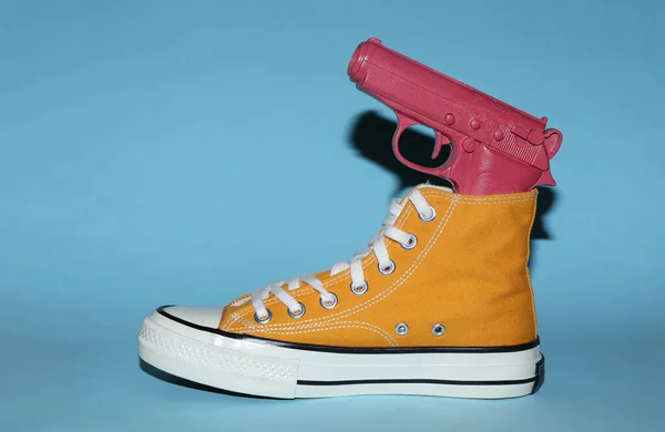 Sneaker Gialla Con Pistola Sfondo Blu Minimalismo Arte Concettuale — Foto Stock