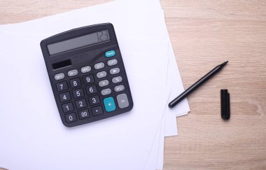 Kağıt çarşaflı ve kalemli siyah klasik hesap makinesi. Üst görünüm