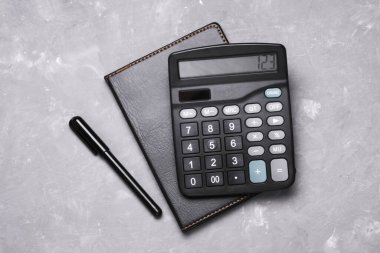 Gri beton arka planda not defteri olan siyah klasik hesap makinesi