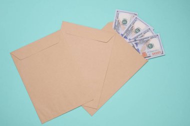 Mavi arka planda 100 dolarlık banknotlar olan zarf. Vergi ödemek