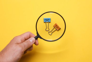 Büyüteçle el ele tutuşup, büyüteçlere, sarı arka plana bakıyorum.