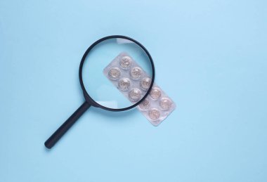 Mavi arka planda hapların su topladığı büyüteç.