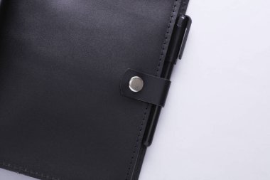 Gri arkaplan üzerinde kalem olan deri dizin ya da defter