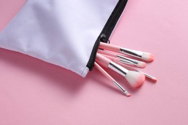Pembe arka planda makyaj fırçası olan beyaz kumaş kozmetik çanta.