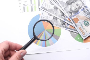 Grafikleri ve grafikleri inceleyen büyüteçle el.