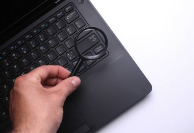 Bir büyüteçle el bilgisayarı inceler. Çöküşleri ara