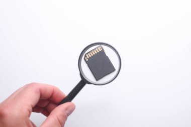 Bir büyüteçle el SD kartı inceler