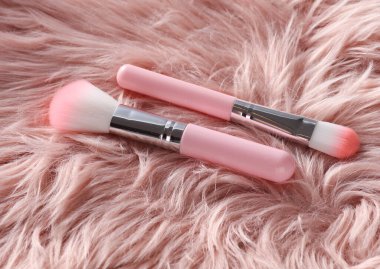 Pembe kürk arka planda makyaj fırçaları