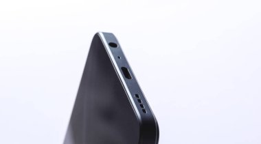 Close-up of charger input, speaker and audio jack of smartphone on white background
