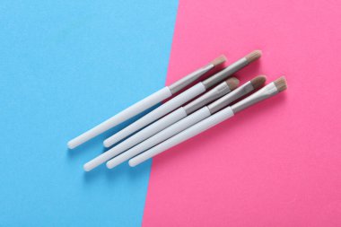 Set of makeup brushes on pink blue background