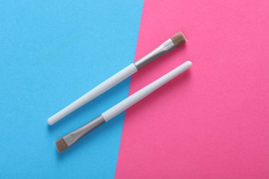 Makeup brushes on pink blue background. Top view
