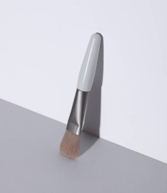 Makeup brush on white gray background. Minimalism, beauty still life