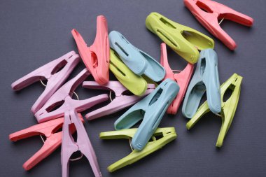 Plastic clothespins on dark gray background. Top view