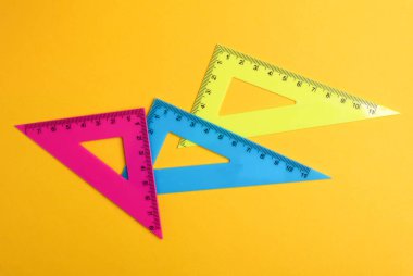 Rulers triangles on yellow background. Top view