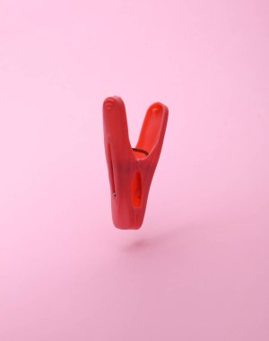 Plastic clothespin floating on pink background