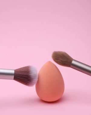 Makeup brushes with egg sponge blender for foundation on pink background