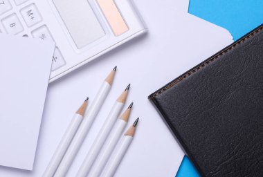 Çalışma alanı, kalemler, kağıtlar ve hesap makinesi. Düz yatıyordu