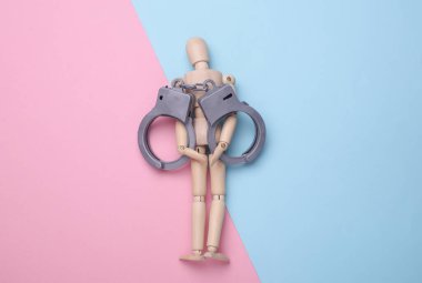 Pembe arka planda kelepçeli tahta kukla.