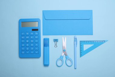 Mavi arka planda okul kırtasiyesi olan zarf. Monokrom fotoğrafçılık. Düz yatıyordu. Yaratıcı yerleşim