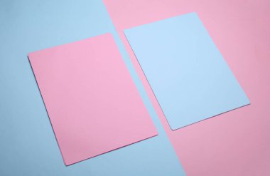 Pastel arka planda A4 büyüklüğünde mavi ve pembe kağıtlar.