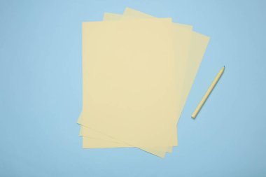 Mavi zemin üzerinde kalem olan sarı kağıtlar