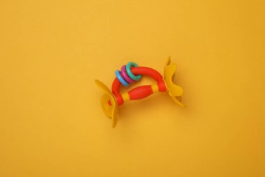 Sarı arka planda yeni doğan bebek için çıngırak oyuncağı