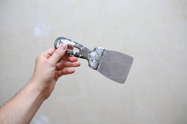 Erkek el arka planda spatulayı tutuyor. Ev yenileme konsepti