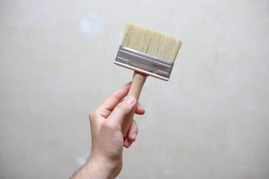 Erkek el fırçayı arka planda tutuyor. Ev yenileme konsepti