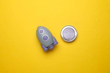 Sarı arka planda pusulası olan oyuncak uzay mekiği. Başlangıç fikri