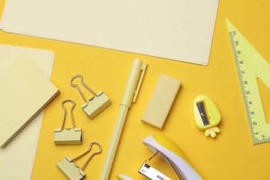 Sarı arka planda kağıt çarşaflı sarı kırtasiye seti. Okula, eğitime, ofis malzemelerine. Düz yatıyordu. Üst Manzara. Tek renkli bir fotoğraf. Yaratıcı yerleşim