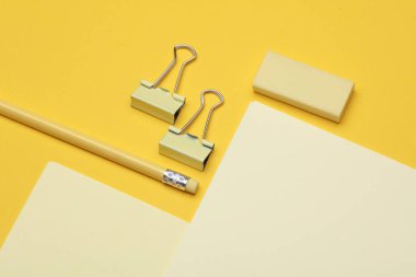 Sarı arka planda kağıt çarşaflı sarı kırtasiye seti. Okula, eğitime, ofis malzemelerine. Düz yatıyordu. Üst Manzara. Tek renkli bir fotoğraf. Yaratıcı yerleşim