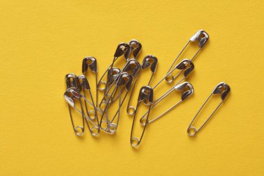 Sarı arkaplanda metal raptiyeler yakın plan